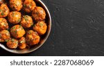 Pan fried little baby potatoes with jeera seeds and coriander in bowl over dark background with free space.  Top view, flat lay