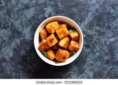 Pan fried paneer. Indian roasted cottage cheese bites in bowl over blue stone background with free text space. Top view, flat lay