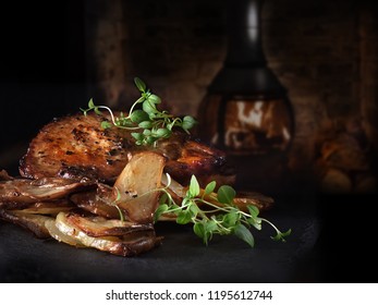 Pan fried, roasted pork fillet steak served with roasted potatoes with thyme garnish. Shot against a dark, rustic background, the perfect image for your restaurant or bistro cover art. Copy space.