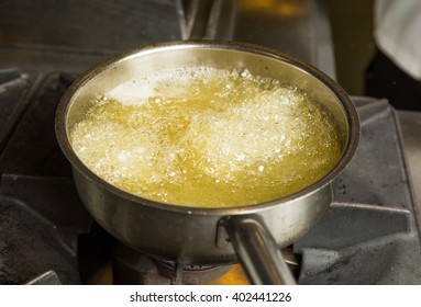 A pan of hot bubbling boiling oil in a silver pan on a hob. - Shutterstock ID 402441226