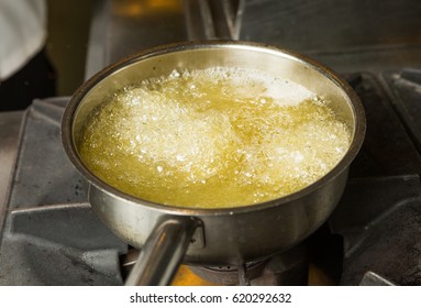 A pan of hot bubbling boiling oil in a silver pan on a hob. - Shutterstock ID 620292632