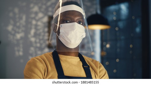 Pan Left Of Young African American Cafe Worker Wearing Self Protection Of Medical Mask And Plastic Shield Standing In Cafeteria