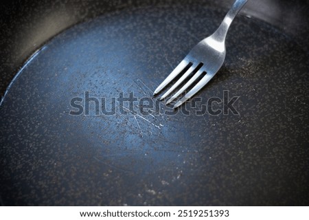 Pan peeling off. Fork in Scratched Teflon non-stick coated pan on stove. Dangerous chemicals in cookware.