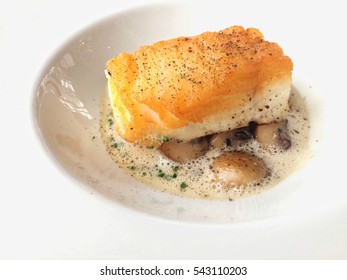 Pan Seared Sea Bass With Mushroom Cream Sauce In White Plate