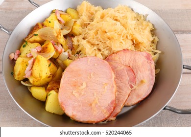 Eine Pfanne mit geräuchertem Schweinekoteletts und Kartoffeln