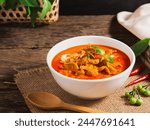 Panang curry with pork in white bowl on wooden table background. Thai Food