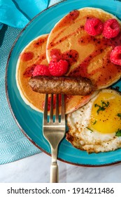 Pancake Breakfast Served With Raspberry Syrup With An Egg And Sausage To Accompany