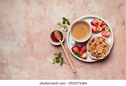 Pancake cereal, mini pancakes with fresh strawberry, milk and honey on a pink background. view from above. - Shutterstock ID 1955571364