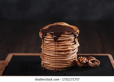 pancake with chocolate and nuts on a black background.
