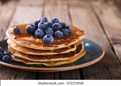 Pancake folded stack of with liquid honey and fresh blueberries on wooden background.selective focus.