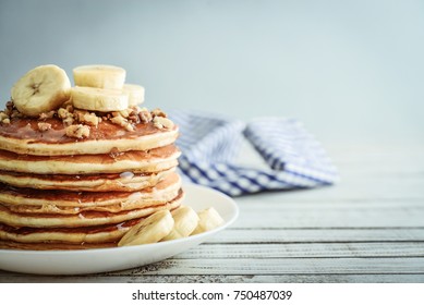 Pancakes with banana,walnut and maple syrup for a breakfast on wooden background closeup
