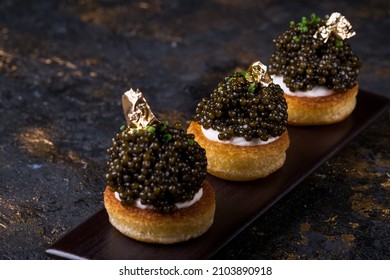 Pancakes With Black Caviar And Gold Leaf On A Background Of Old Wooden Surfaces