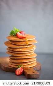 Pancakes for breakfast. Cover with pancakes. A stack of pancakes on a wooden board with honey. Honey pours on pancakes. Dessert. Favorite breakfast. Beautiful food cover.American breakfast. 