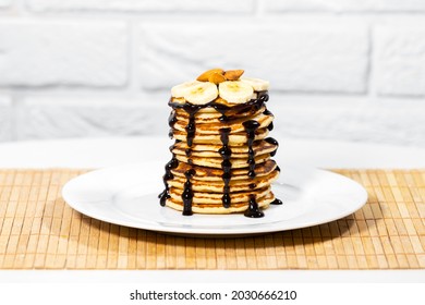 Pancakes with Chocolate Syrup, Nuts and Bananas. Stack of whole flapjack. Tasty breakfast and Healthy Food, Homemade baked dessert