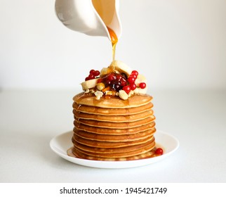 Pancakes are decorated with berries and banana and are poured with maple syrup or honey. - Powered by Shutterstock