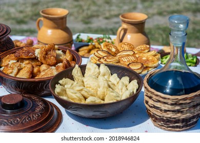 Lot Of Pancakes, Dumplings And Wine On The Table In Yard, Close Up, Ukraine. Traditional Ukrainian Food