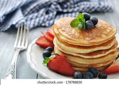 Pancakes with fresh berries, mint and maple syrup on white plate closeup - Powered by Shutterstock