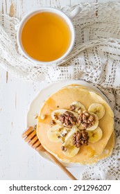 Pancakes With Honey, Banana, Nuts, Tea, White Wood Background, Top View