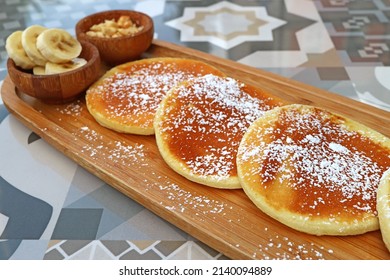 Pancakes With Icing Sugar On Wooden Plate Served On Patterned Stone Table