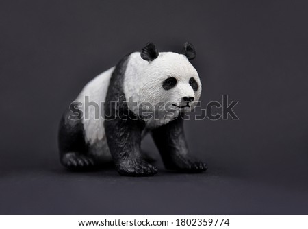 Panda bear plastic toy stock images. Giant panda cute figurine isolated on a black background. Sitting panda bear figurine stock images