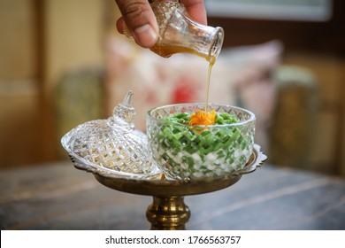 Pandan flavored rice flour droplets with shredded egg yolk topping in glass bowl and pouring sweetened coconut cream syrup or 'Lod Chong' in Thai language, It's tasty dessert of asian.