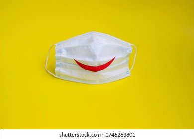 Pandemic End Concept. End Of Quarantine. Medical Mask With A Smile On A Bright Yellow Background. Copy Space. High Quality Photo