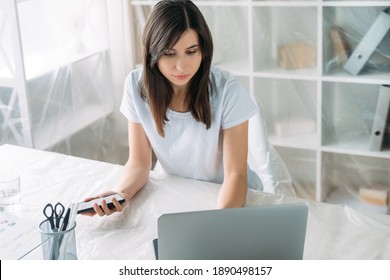 Pandemic Furlough. Office Relocation. Business Shutdown. Thoughtful Woman Employee Looking For New Job With Laptop Phone In Light Room With Furniture Covered With Polyethylene Film.