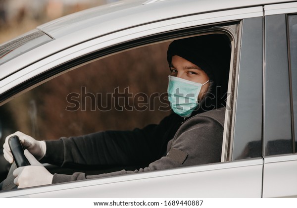 Pandemic outbreak. Man in the medical mask and\
rubber gloves for protect himself from bacteria and virus while\
driving a car. masked man in a car. coronavirus, disease,\
infection, quarantine,\
covid-19
