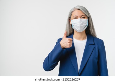Pandemic, social distance, isolation concept. Caucasian mature middle-aged businesswoman teacher bank manager wearing protective face mask against coronavirus showing thumb up isolated in white - Shutterstock ID 2152526237