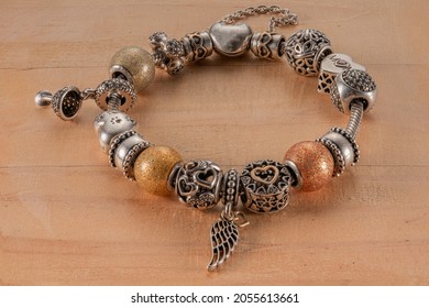 Pandora bracelet with different charms on a wooden base, focused completely - Shutterstock ID 2055613661