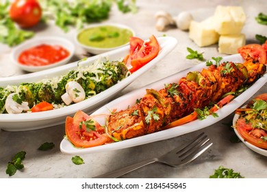 Paneer kabab photography veg dish. Green masala and red masala garnished in plate styled with fresh ingredients like coriander tomato mushrooms pudina chutney tomato ketchup and raw fresh penner.      - Powered by Shutterstock