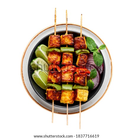 Paneer Tikka at skewers isolated on white background. Paneer tikka is an indian cuisine dish with grilled paneer cheese with vegetables and spices. Indian food. Top view
