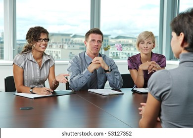 Panel of business people sitting at table in meeting room conducting job interview talking with applicant. - Powered by Shutterstock