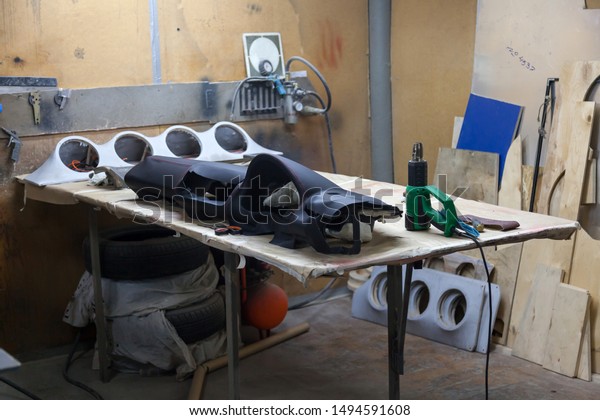 The panel of the car interior on a workbench\
in a workshop for repair and hauling of vehicle elements with\
leather or other materials.