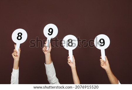 Panel of judges holding different score signs on brown background, closeup