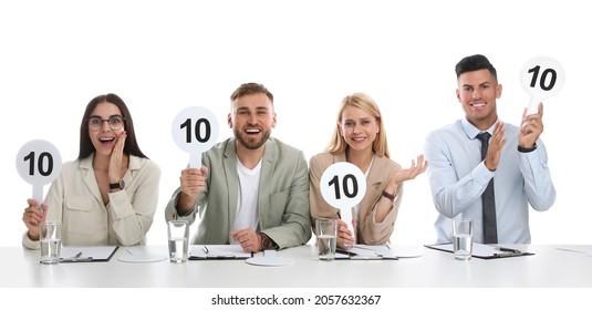 Panel of judges holding signs with highest score at table on white background - Powered by Shutterstock