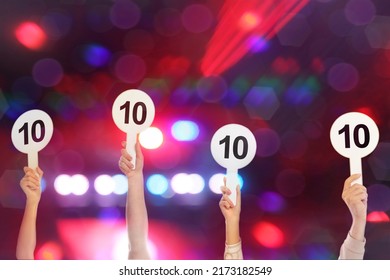 Panel of judges holding signs with highest score against blurred background, closeup. Bokeh effect - Powered by Shutterstock