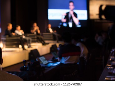 Panel Speaker on Stage Presenting Vision and Ideas. Conference Lecture Hall. Blurred De-focused Unidentifiable Presenter and Audience. People Attendees. Business Technology Event. Debate Discussion.