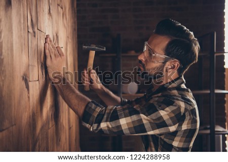 Panel wooden board designer people person concept. Side profile close up photo portrait of serious concentrated guy hammering nail into wall hold metallic tool equipment instrument