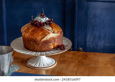 Panettone bread with cherries and whipped cream on a holiday table at Christmas.