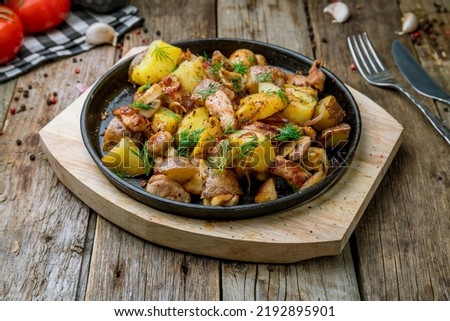 pan-fried chicken with potatoes and mushrooms on old wooden table