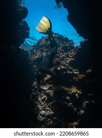 Panglao, Philippines - 23.05.2022: Male Freediver Fun Diving Descending Into Reef Crack In The Ocean Sea Holding Breath Wearing Mono Fin