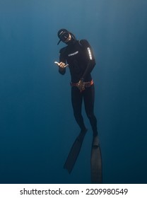 Panglao, Philippines - 28.04.2022: Male Freediver Wearing Wetsuit Ascending To The Surface Holding Breath In The Sea Ocean Posing Fooling Around