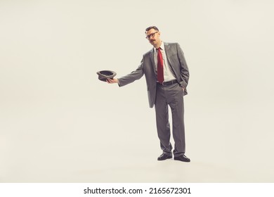 Panhandle. One businessman wearing grey striped suit in 50s, 60s fashion style holding hat isolated on white background. Concept of sales, rights, diversity, fashion and ads. Human rights, choice