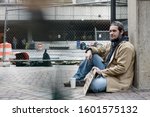 Panhandler sitting while blurred pedestrians pass him by