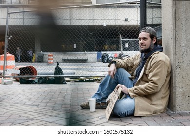 Panhandler Sitting While Blurred Pedestrians Pass Him By