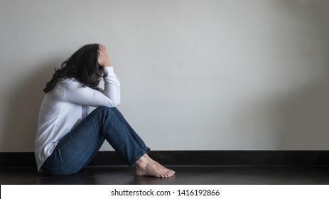 Panic attack woman, stressful depressed emotional person with anxiety disorder mental health illness, headache and migraine sitting against wall in domestic home floor for metoo (me too) concept
