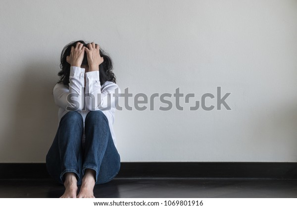 Panic attack woman, stressful depressed emotional\
person with anxiety disorder mental health illness, headache and\
migraine sitting feeling bad with back against wall on the floor in\
domestic home