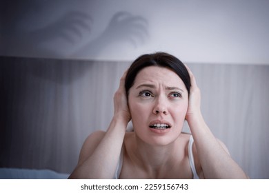 Panic attack in women. The depressed young lady sitting on couch hugging head with hands. Psychological problem concept. - Shutterstock ID 2259156743