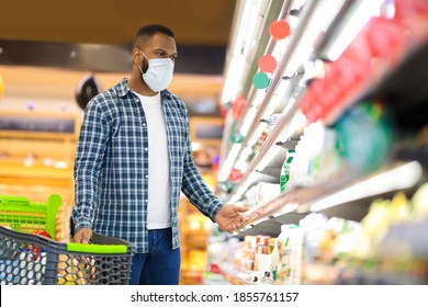 Panic Buying During Pandemic. Black Man Shopping In Supermarket Buying Food Wearing Face Mask, Guy Looking At Shelf Preparing For Coronavirus Quarantine Lockdown Standing In Grocery Store. Copy Space